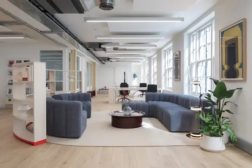 Breakout Space at Fairfax House London with curved navy blue couches a round red coffee table and a curved bookshelf