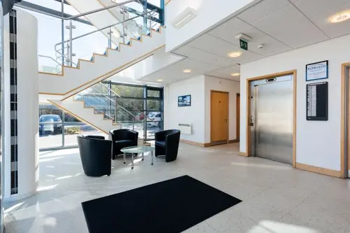 Reception area at Barnsley Carlton with three black leather chairs around a small round glass coffee table